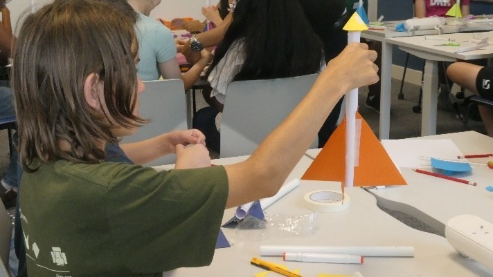 A student building a paper rocket with nose cone and stabilising fins