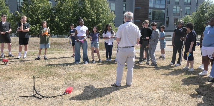 A group of students outside launching a paper rocket with an air foot pump