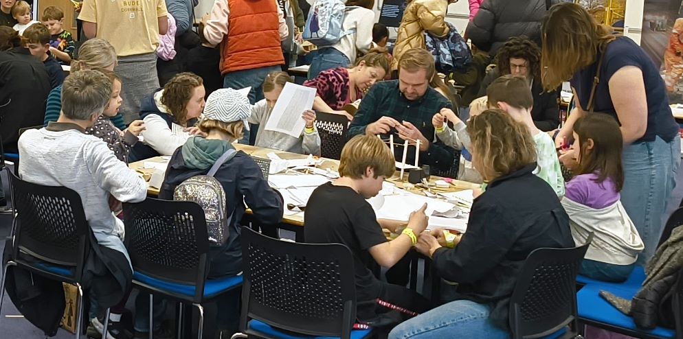 A group of children and parents building structures out of paper and spaghetti