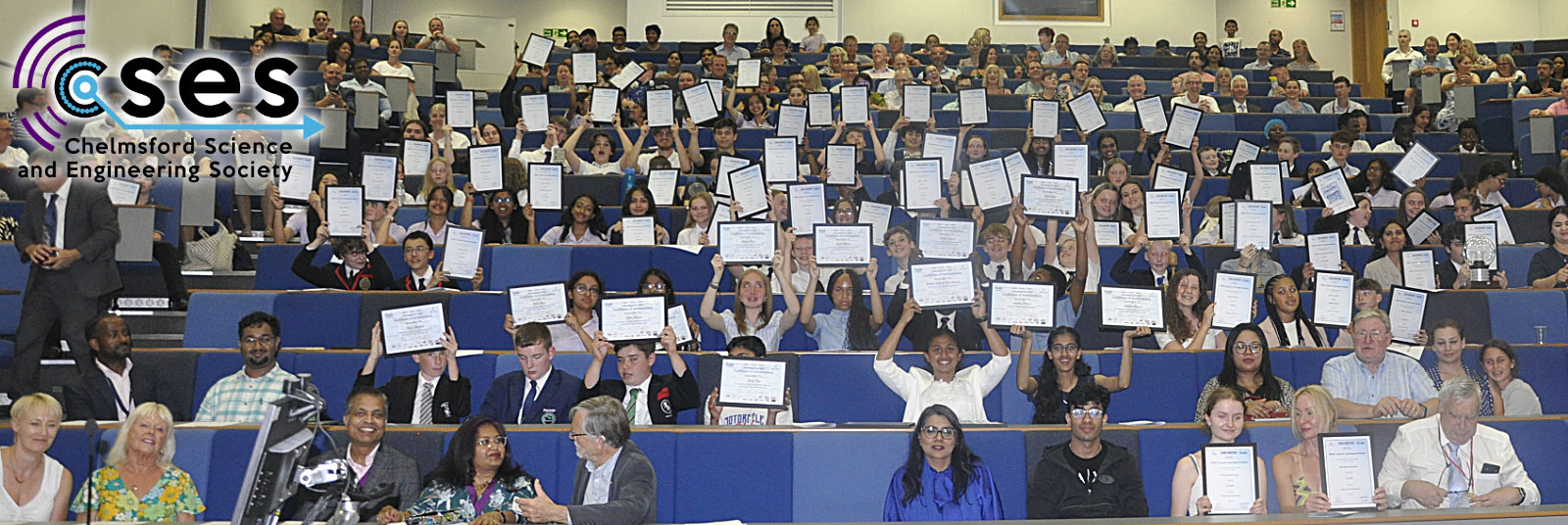 A large group photo of students, teachers and parents enjoying the awards evening and holding up their certificates in celebration