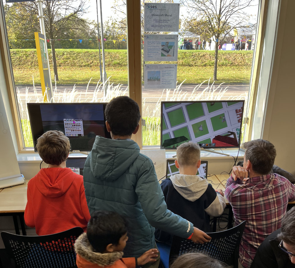 A group of children and their parents playing on the Minecraft mural