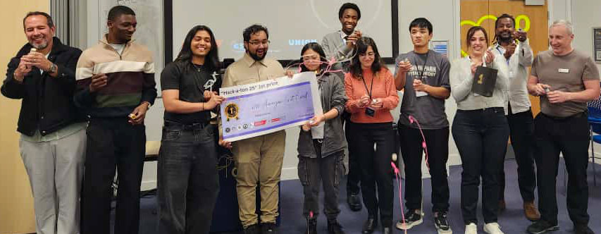 A team of students being presented with a giant cheque by CSES volunteers 